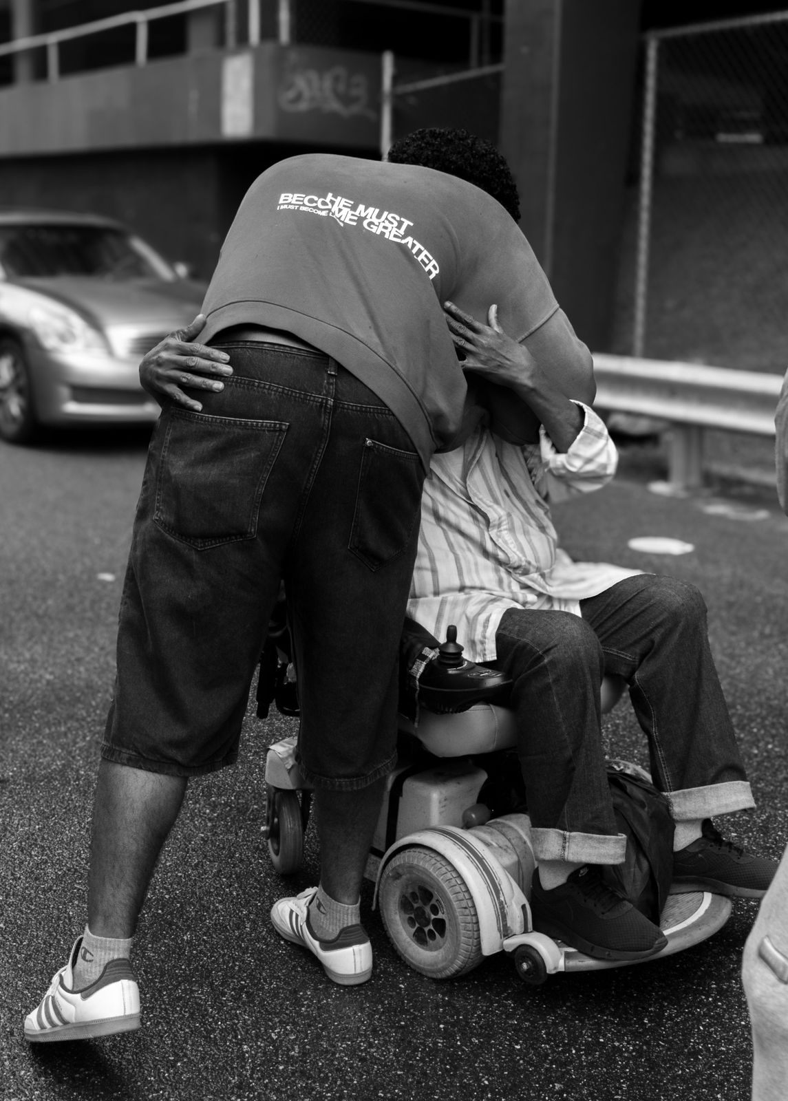 A volunteer hugging a man in a wheelchair