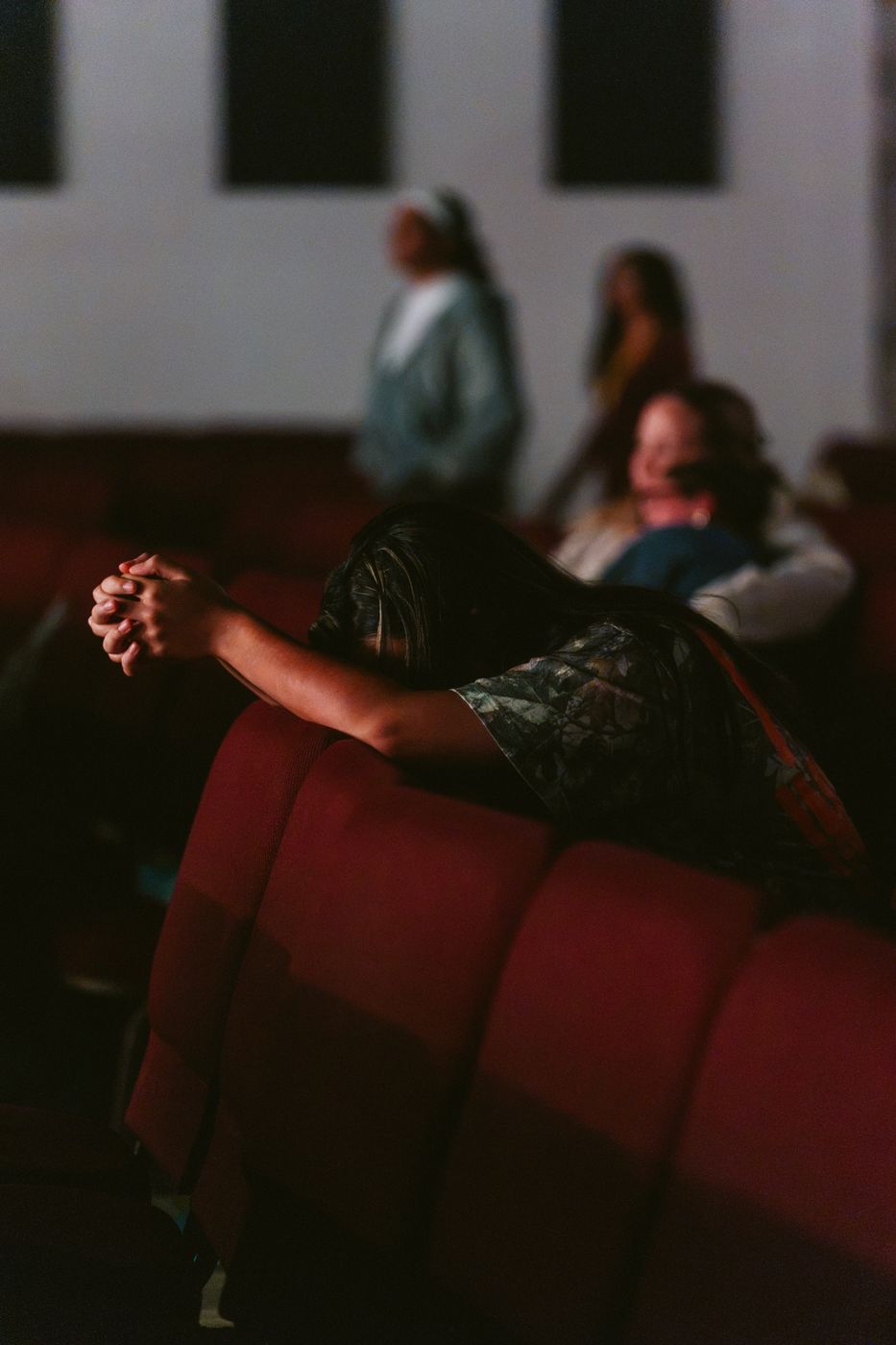 Someone bowed in prayer over the pews