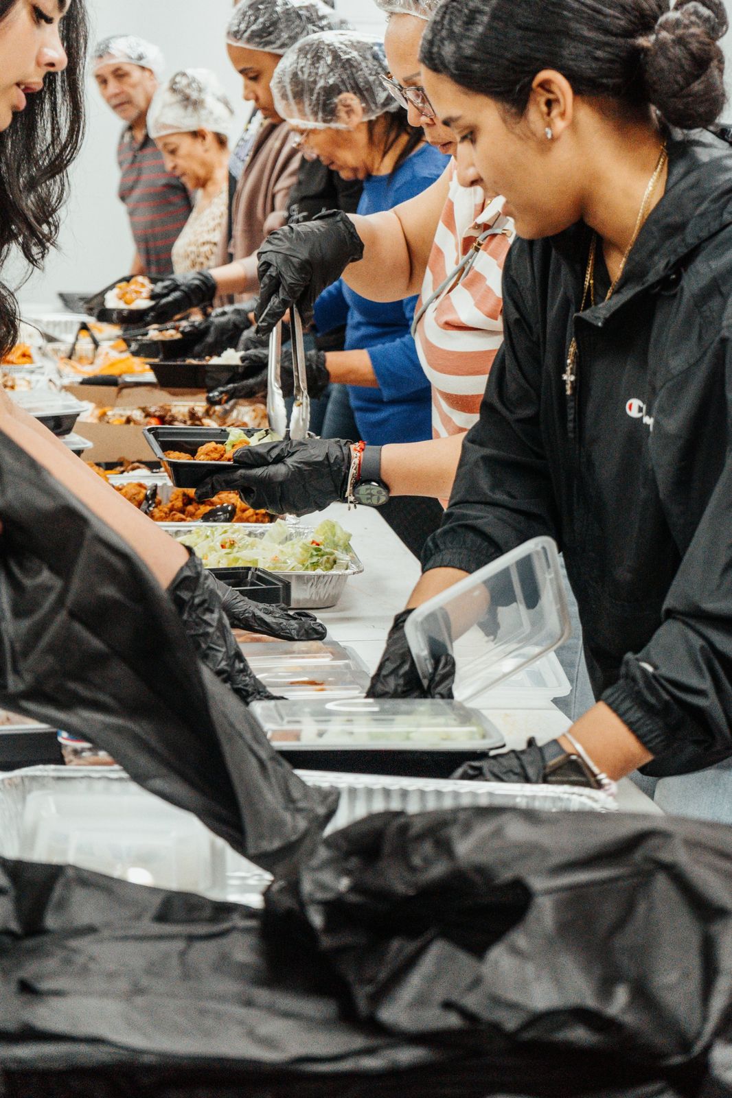Volunteers in gloves filling meal containers
